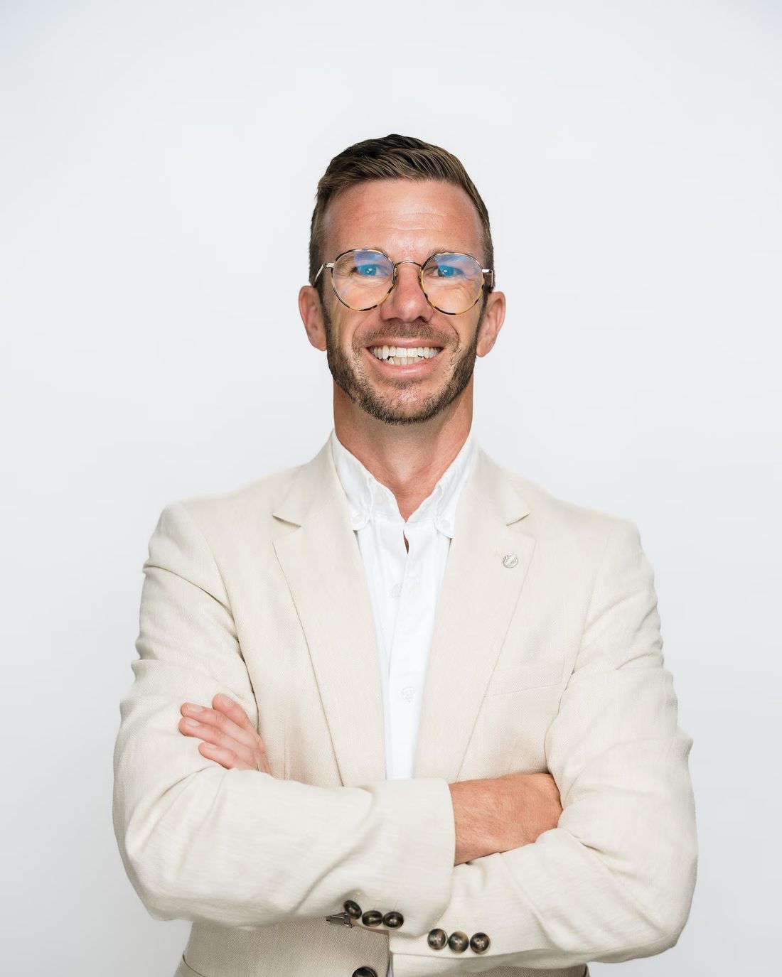 Hayden Judd in a cream blazer, arms crossed, smiling